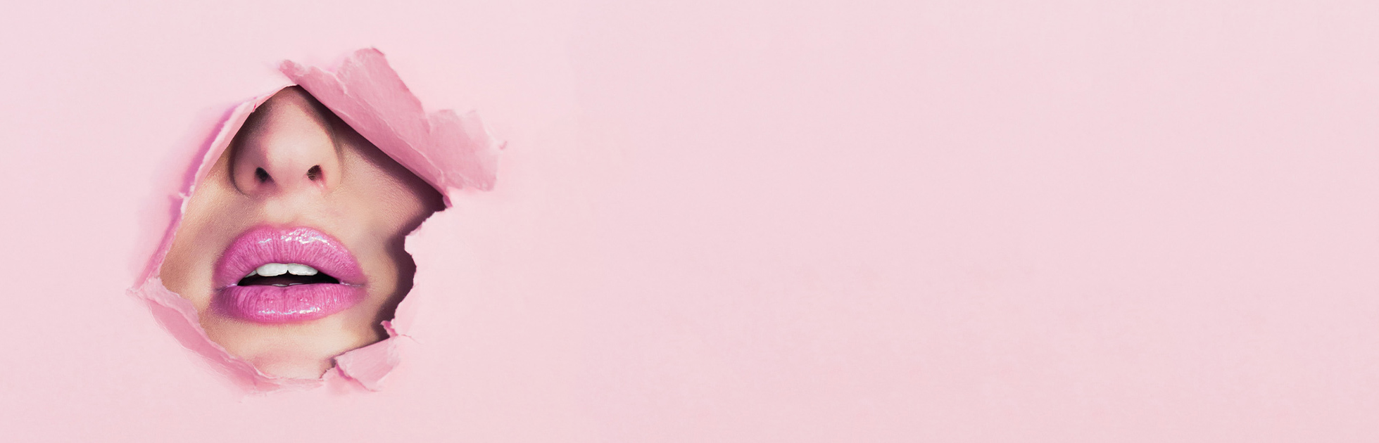 Ein Gesicht ragt durch rosafarbenes Papier, rosa geschminkte Lippen sichtbar